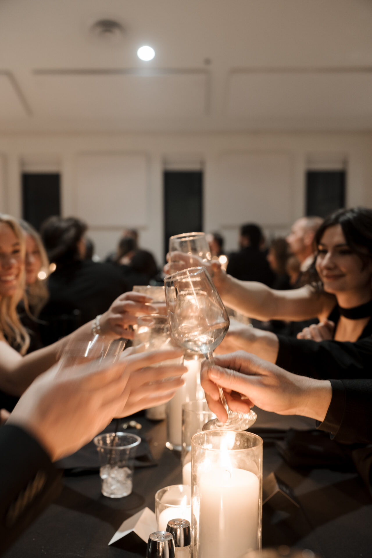 editorial and candid photo of guests cheers during toasts at wedding reception in cande light