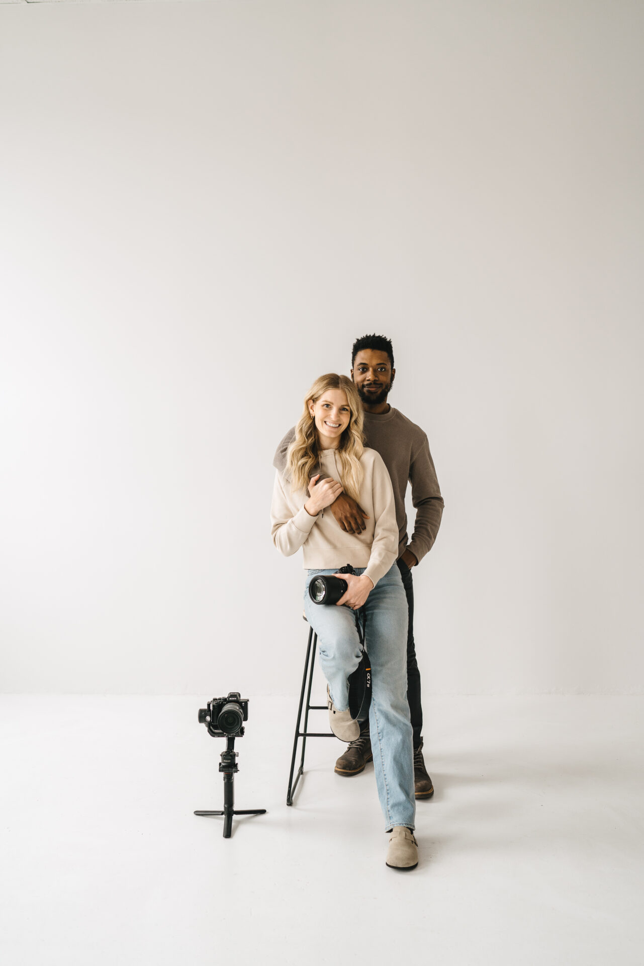 husband and wife photo and video team sitting on a stool for branding photo