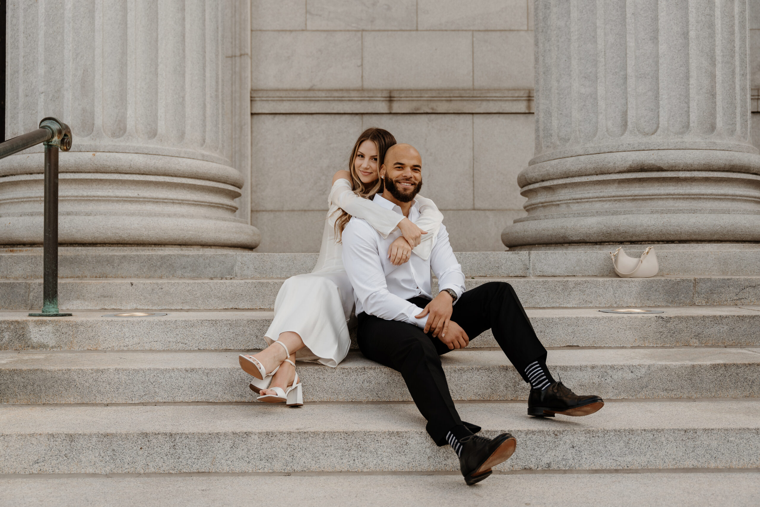 couple sitting on white staircase taking engagement pictures in minneapolis