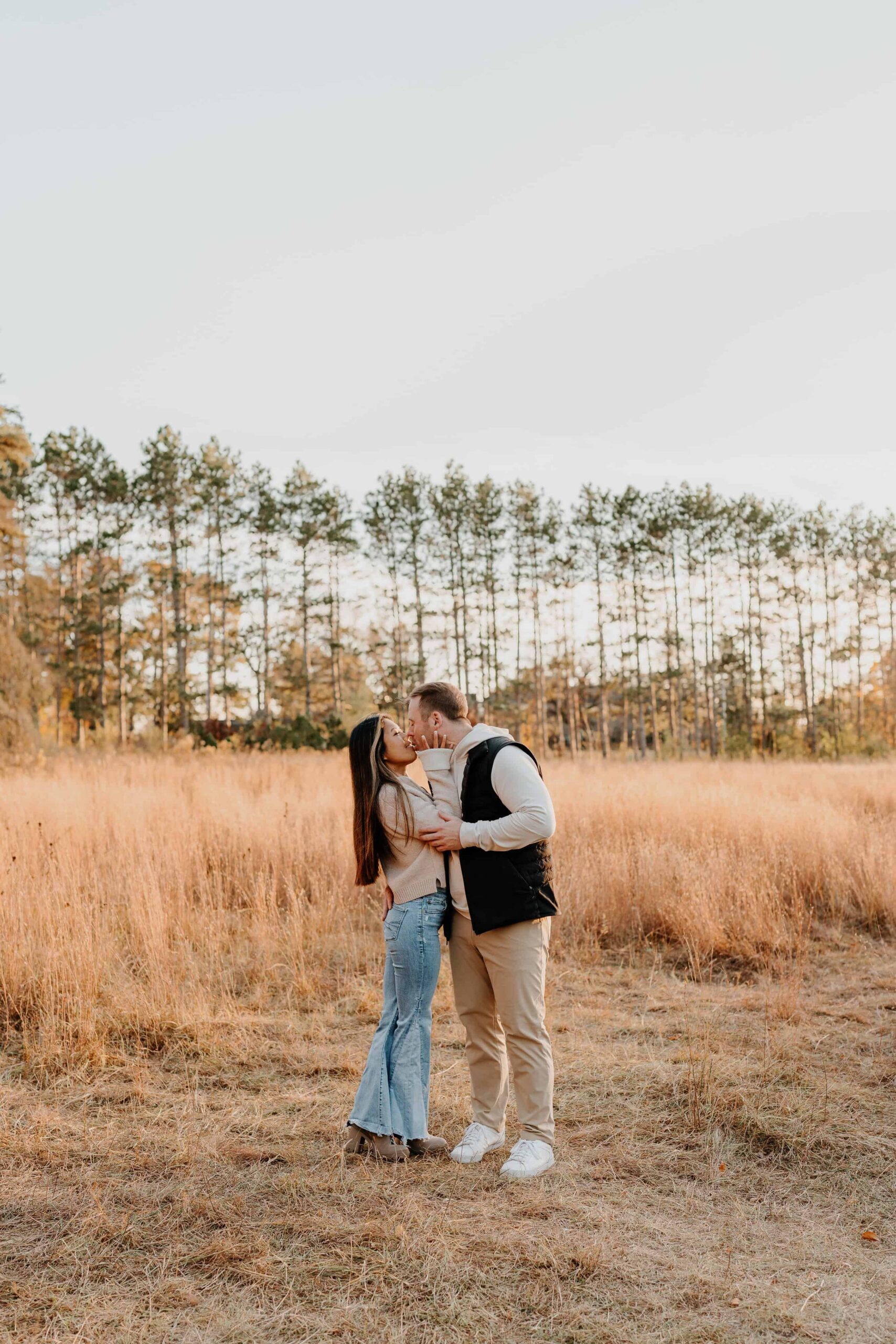 couple kissing during engagement photos with pine trees in the background