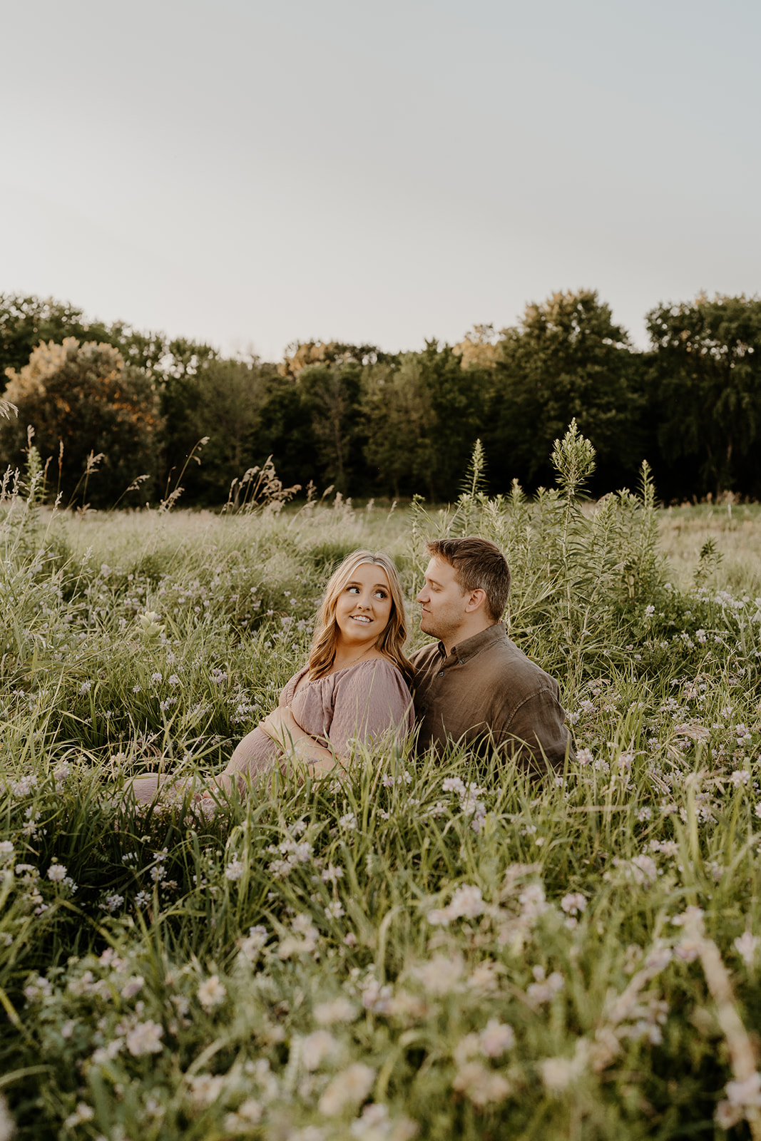 expecting couple sitting in field taking maternity photoshoot