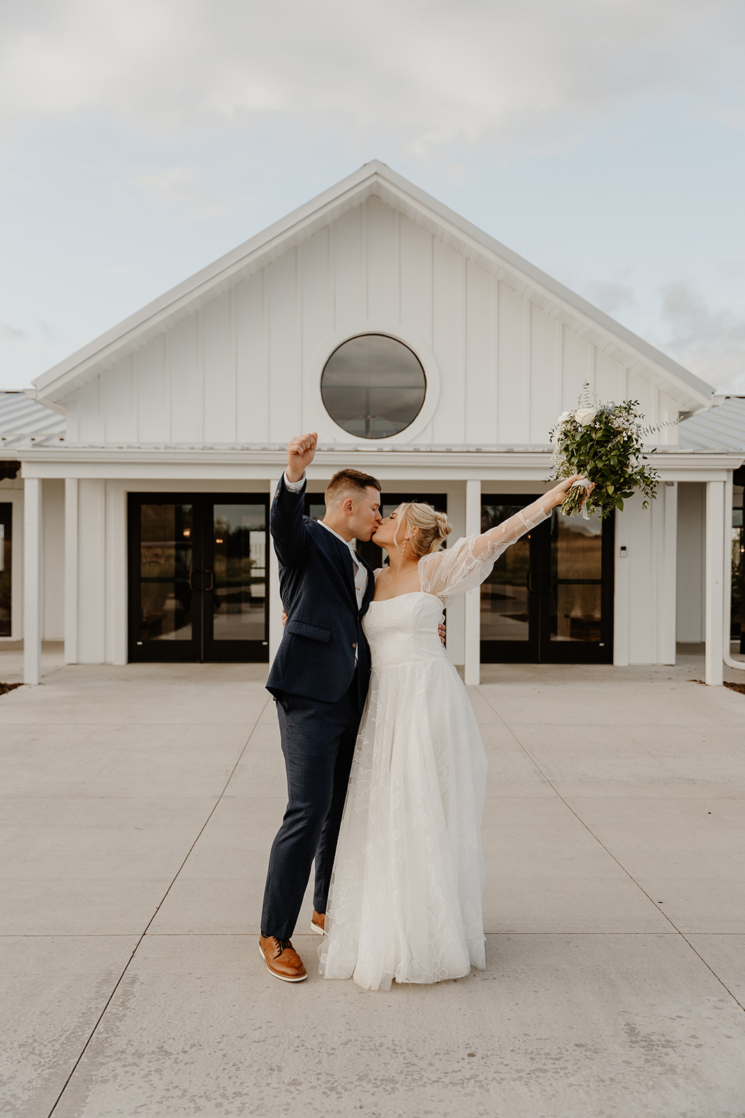 bride and groom celebrating in front of modern white wedding venue